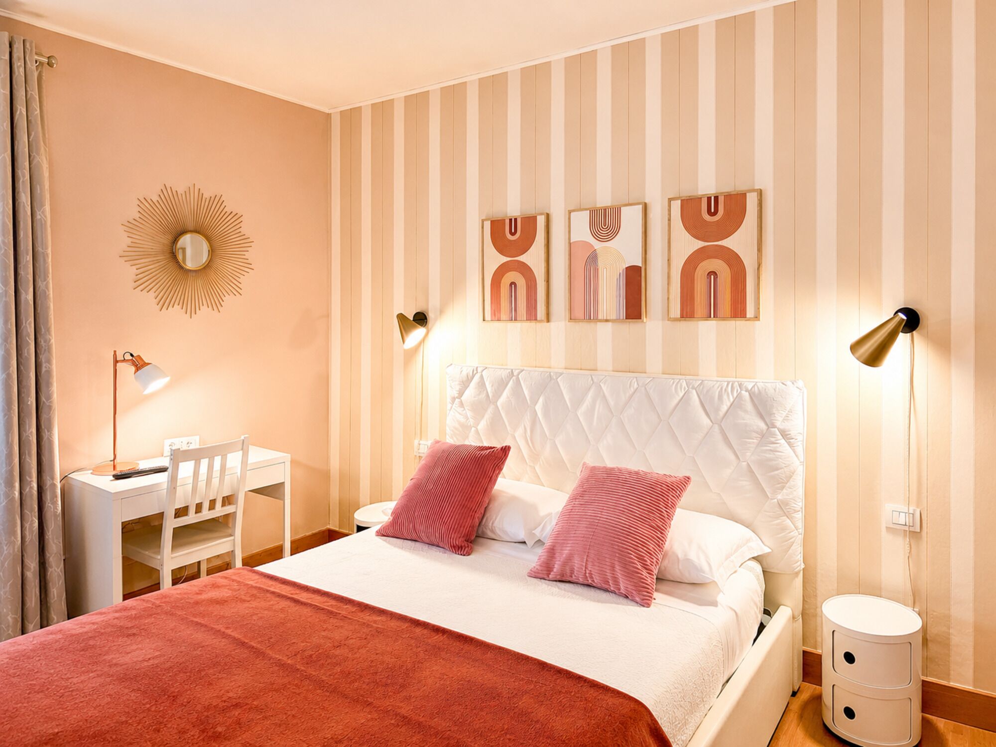 Ein Schlafzimmer mit einem Bett, Nachttischen, einem Schreibtisch und einem an der Wand befestigten Spiegel.