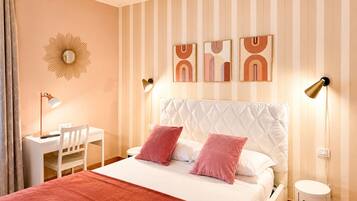 Ein Schlafzimmer mit einem Bett, Nachttischen, einem Schreibtisch und einem an der Wand befestigten Spiegel.