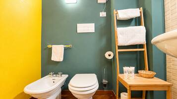 Ein Badezimmer mit integriertem Bidet, Toilette, Handtuchhalter und einem Holzboden mit Pflegeprodukten.