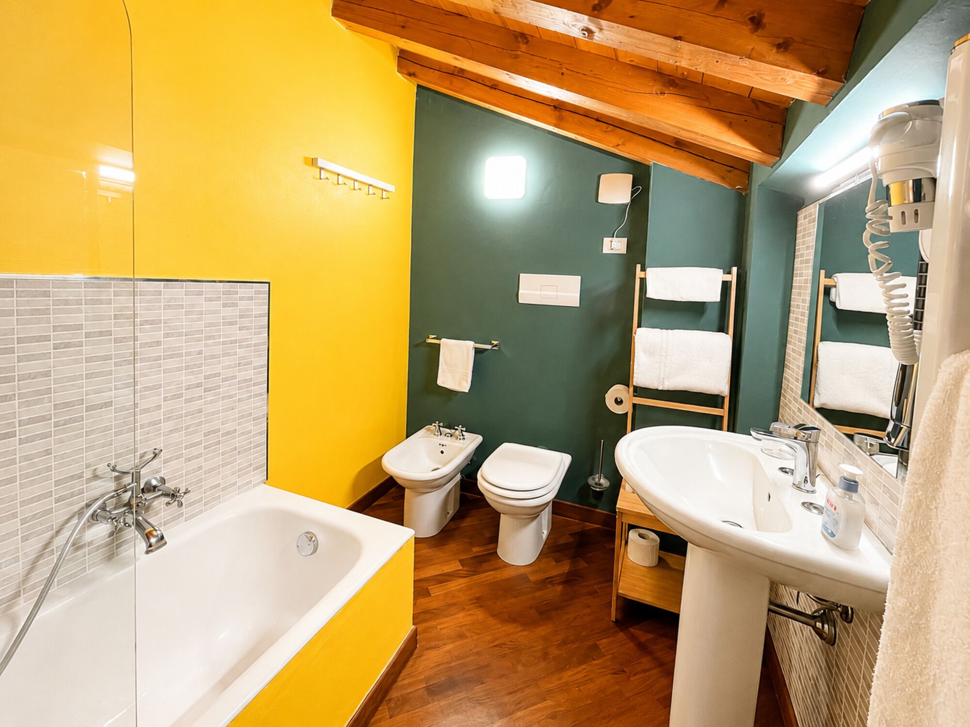 Un baño con una bañera, dos inodoros, un lavabo y un espejo.