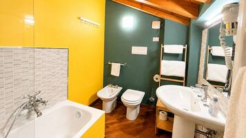 Un baño con una bañera, dos inodoros, un lavabo y un espejo.