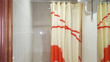 A bathroom with a shower curtain, tiled walls, and a wooden door.