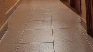 Um corredor com portas em ambos os lados, um radiador à direita e um candeeiro à esquerda.