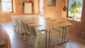 Une salle de conférence avec une longue table, des chaises, un tableau blanc et un tableau accroché au mur.