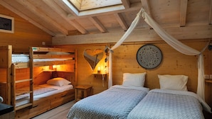 A cozy wooden cabin bedroom with bunk beds, a canopy bed, a heart-shaped wall decoration, and a circular wall hanging. - Domaine du Hirtz (Wattwiller)