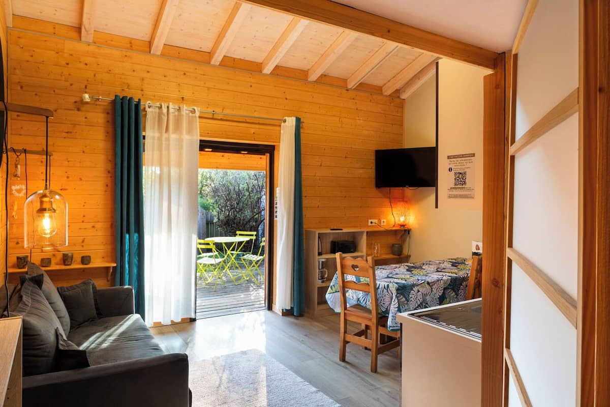 Een gezellige kamer met houten plafond, een bank, een tafel met stoelen en uitzicht op de omgeving.