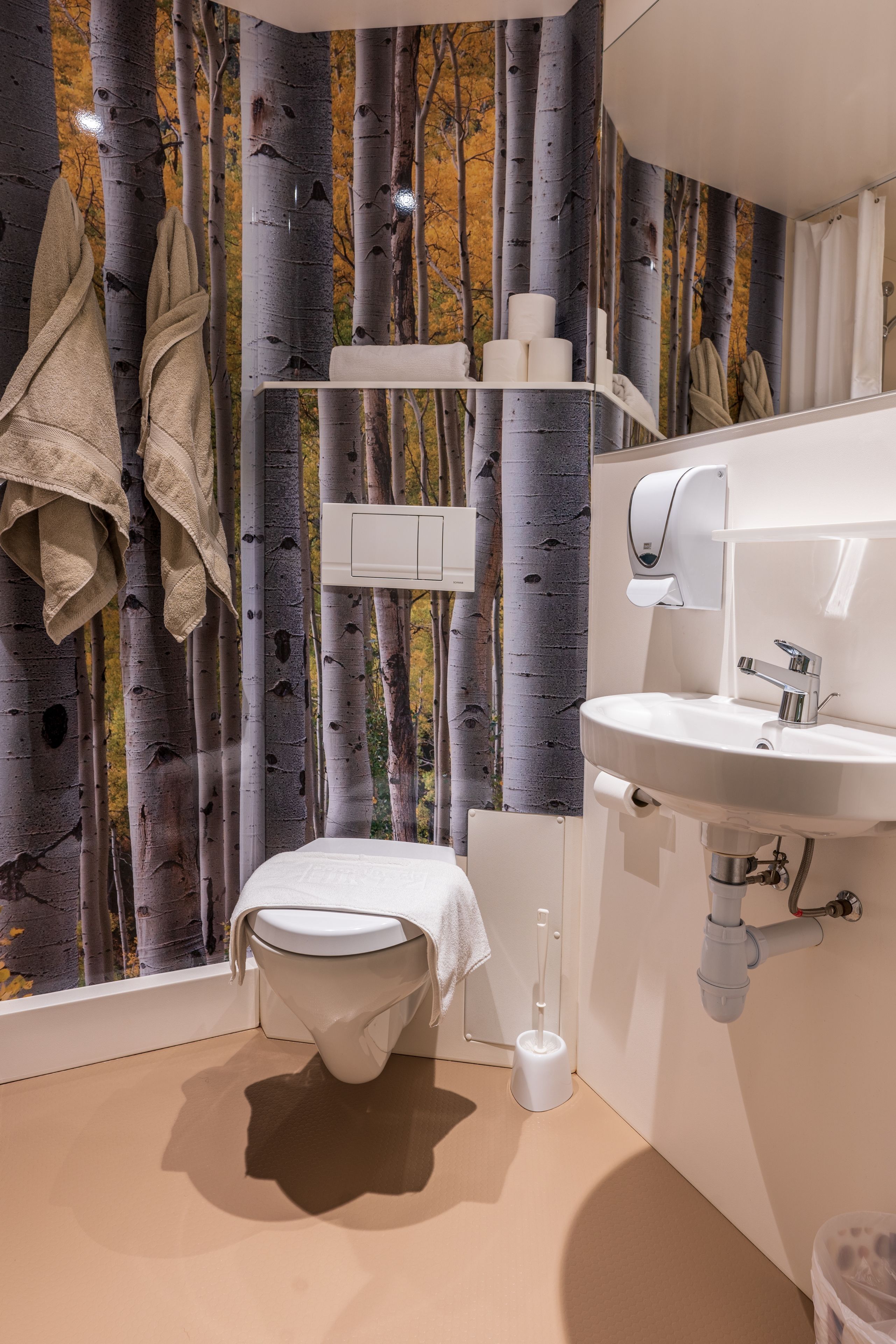 A modern bathroom with a toilet, sink, and hand dryer.
