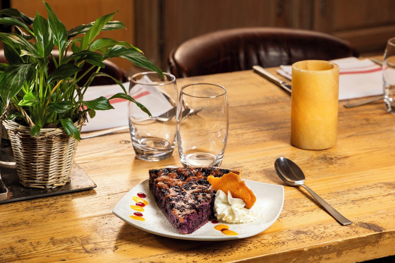 Une assiette à dessert avec une part de gâteau et une cuillerée de crème, posée sur une table en bois.