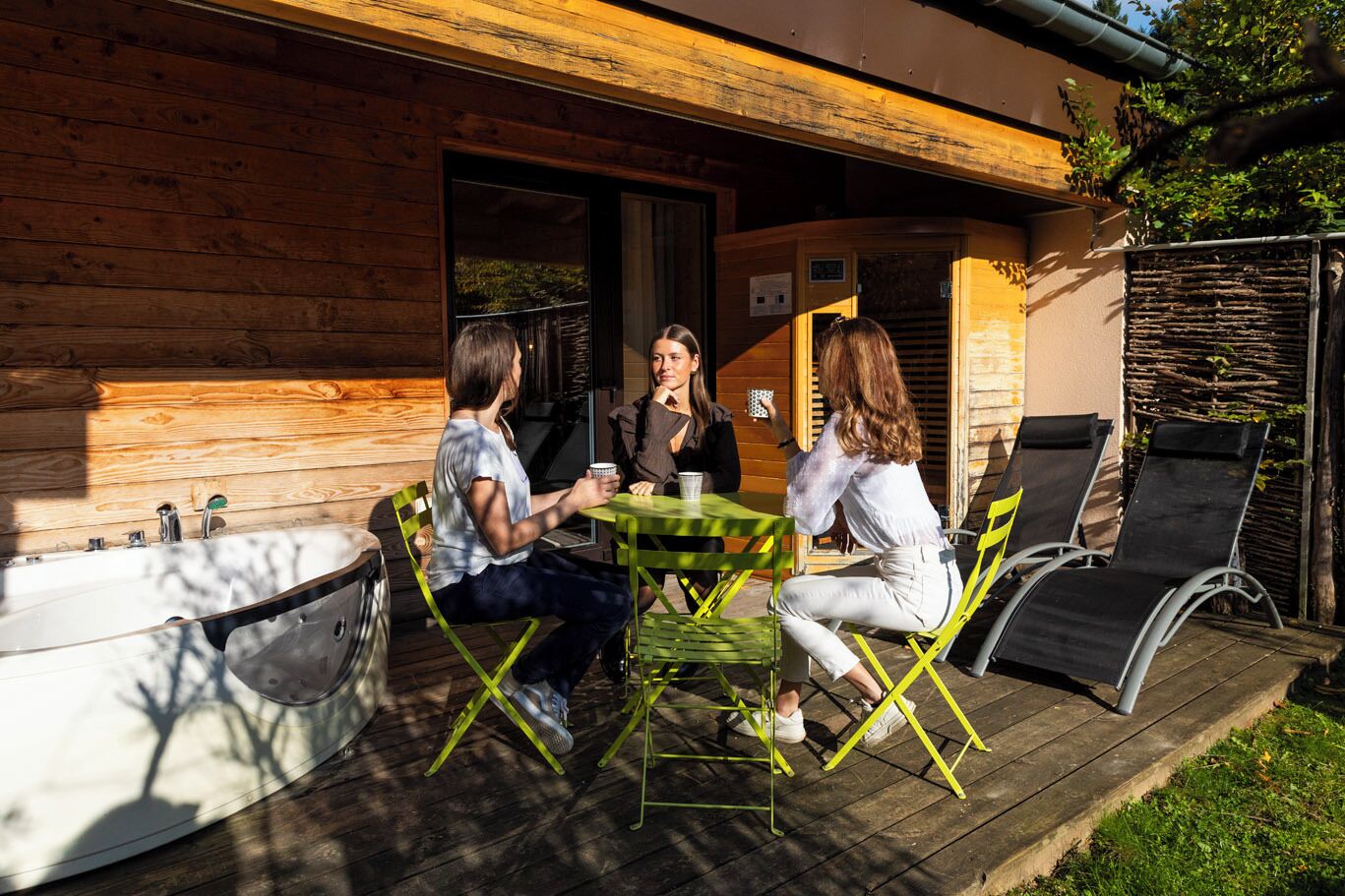 A wooden cabin with a deck, a table, and chairs.
