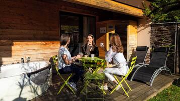 A wooden cabin with a deck, a table, and chairs.