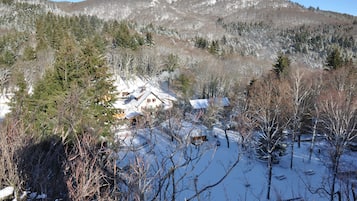 Una cabaña rodeada de árboles y montañas cubiertas de nieve.