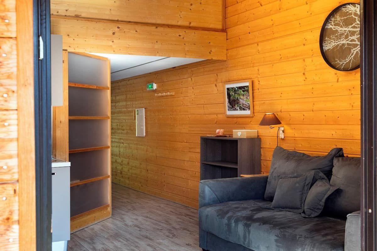 Een houten interieur met een bank, een klein tafeltje en een wandlamp.