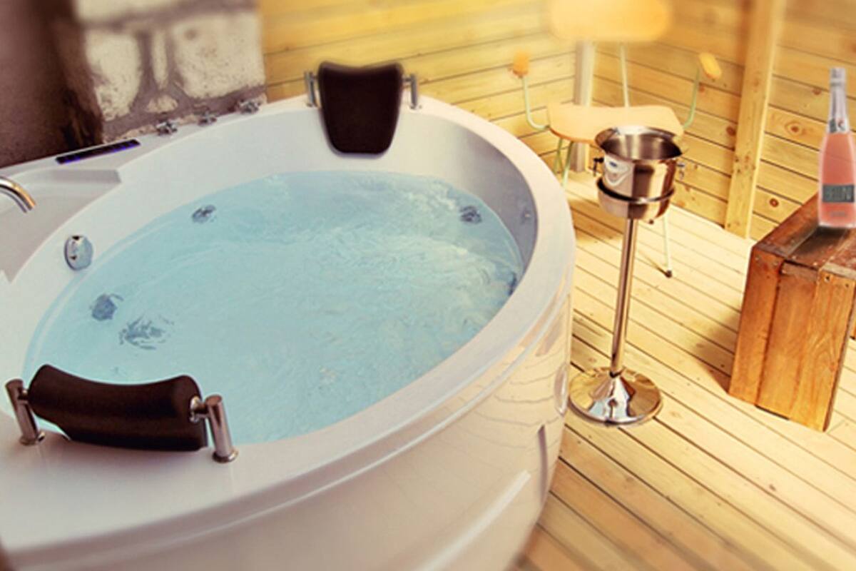 A hot tub with a wooden deck, a metal stand, and a bottle of champagne.