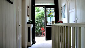 A hallway with a door leading to a balcony with a red chair and a flower arrangement. - La Villa Paris (Paris)