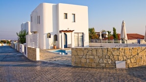 Un bâtiment moderne, de couleur blanche, avec un mur en pierre et une piscine.
