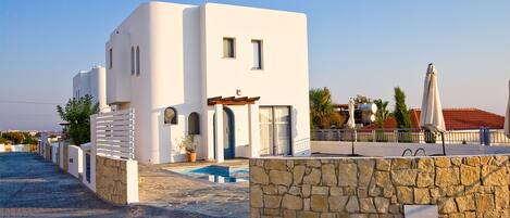 Un edificio moderno blanco con un muro de piedra y una piscina.