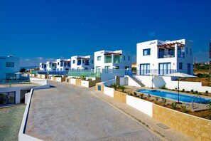 Un edificio residencial moderno con piscina, fachada blanca y balcones.