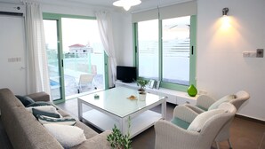 Un salon moderne avec un canapé, une table basse en verre et des fauteuils en osier.