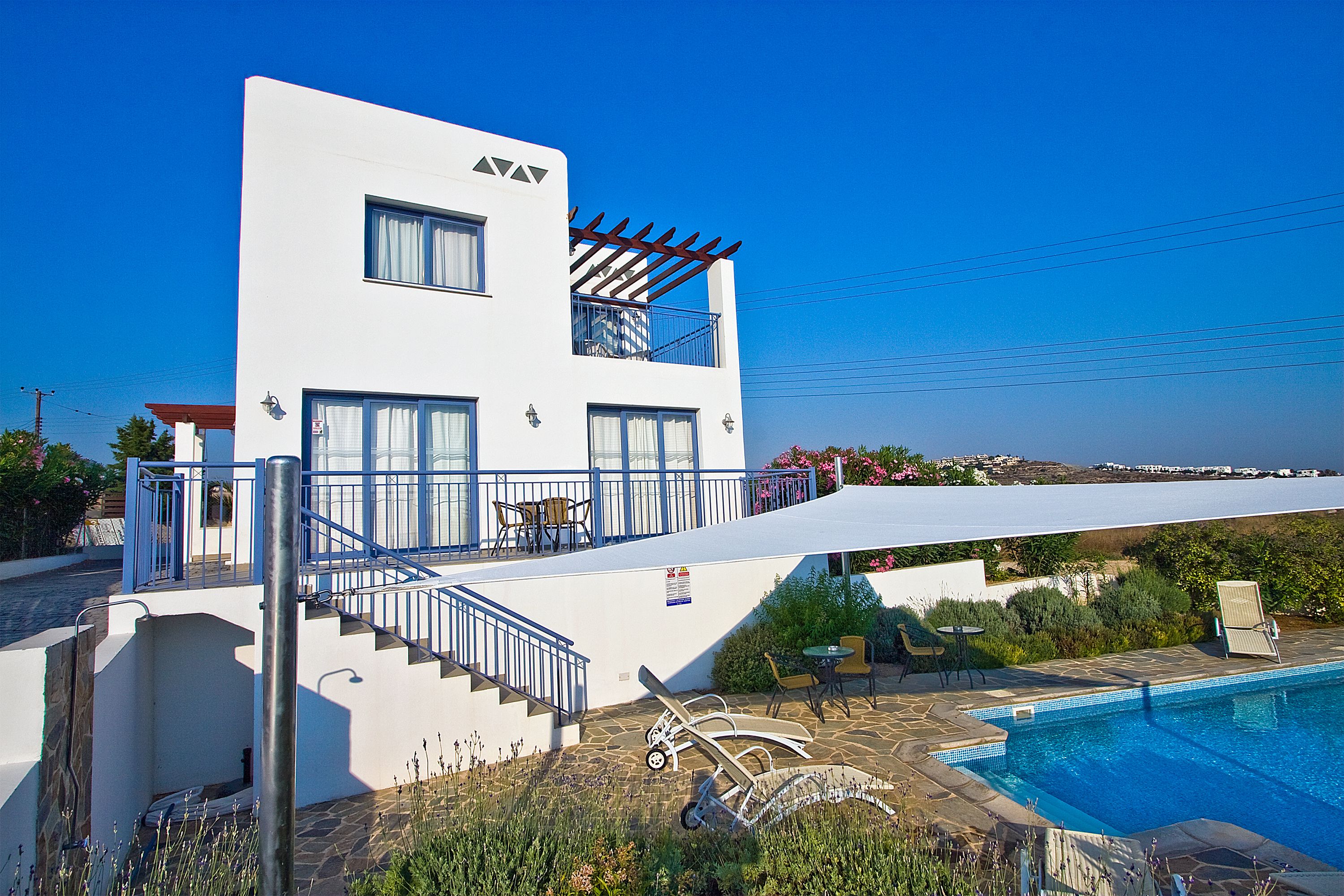 A modern building with a pool, outdoor seating, and a view of the sea.