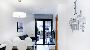 A modern dining area with a white table and chairs, a pendant light, and a wall with motivational words. - Home To Home Barcelona (Barcelona)
