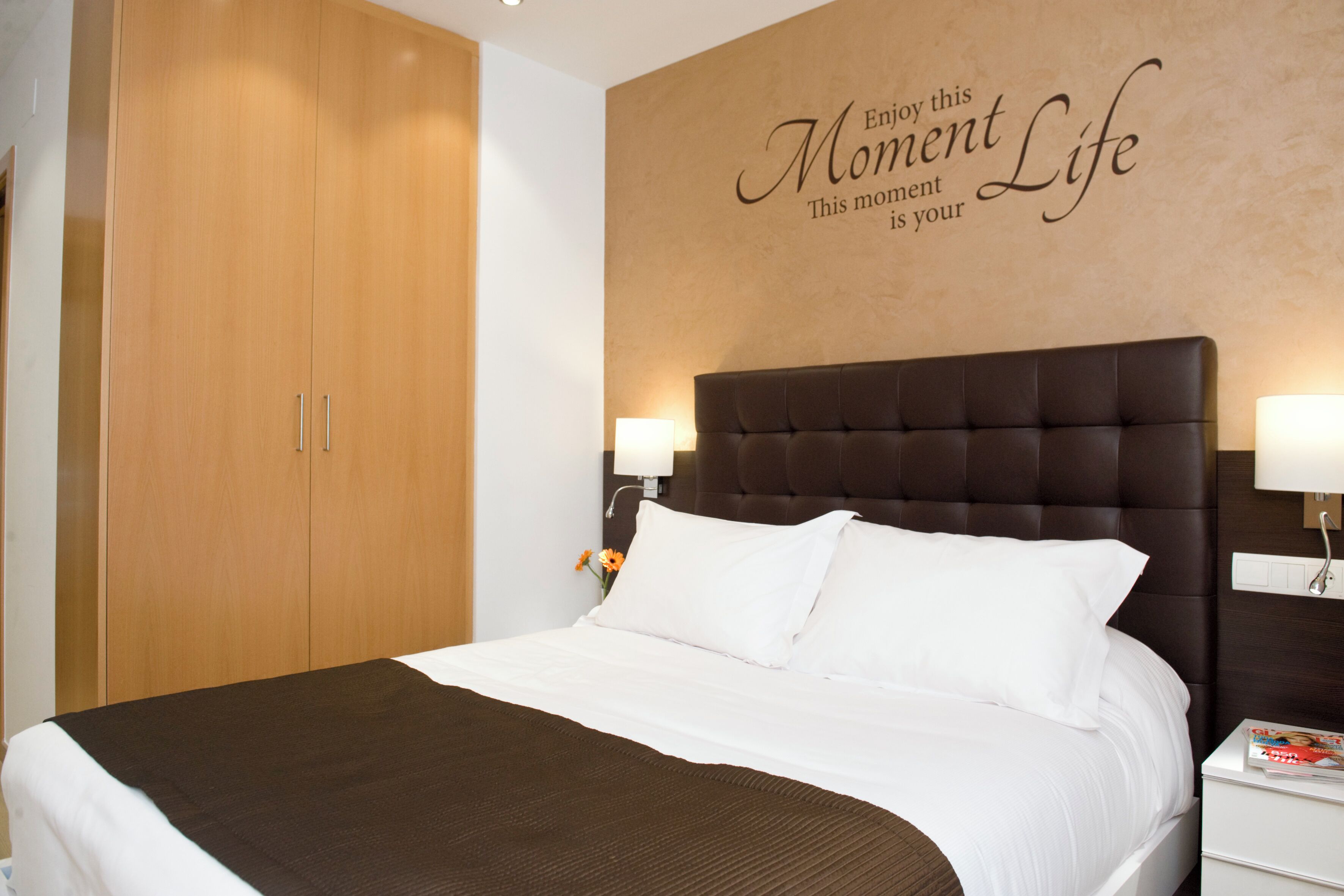 A hotel room with a large bed, a wardrobe, and a motivational quote on the wall.