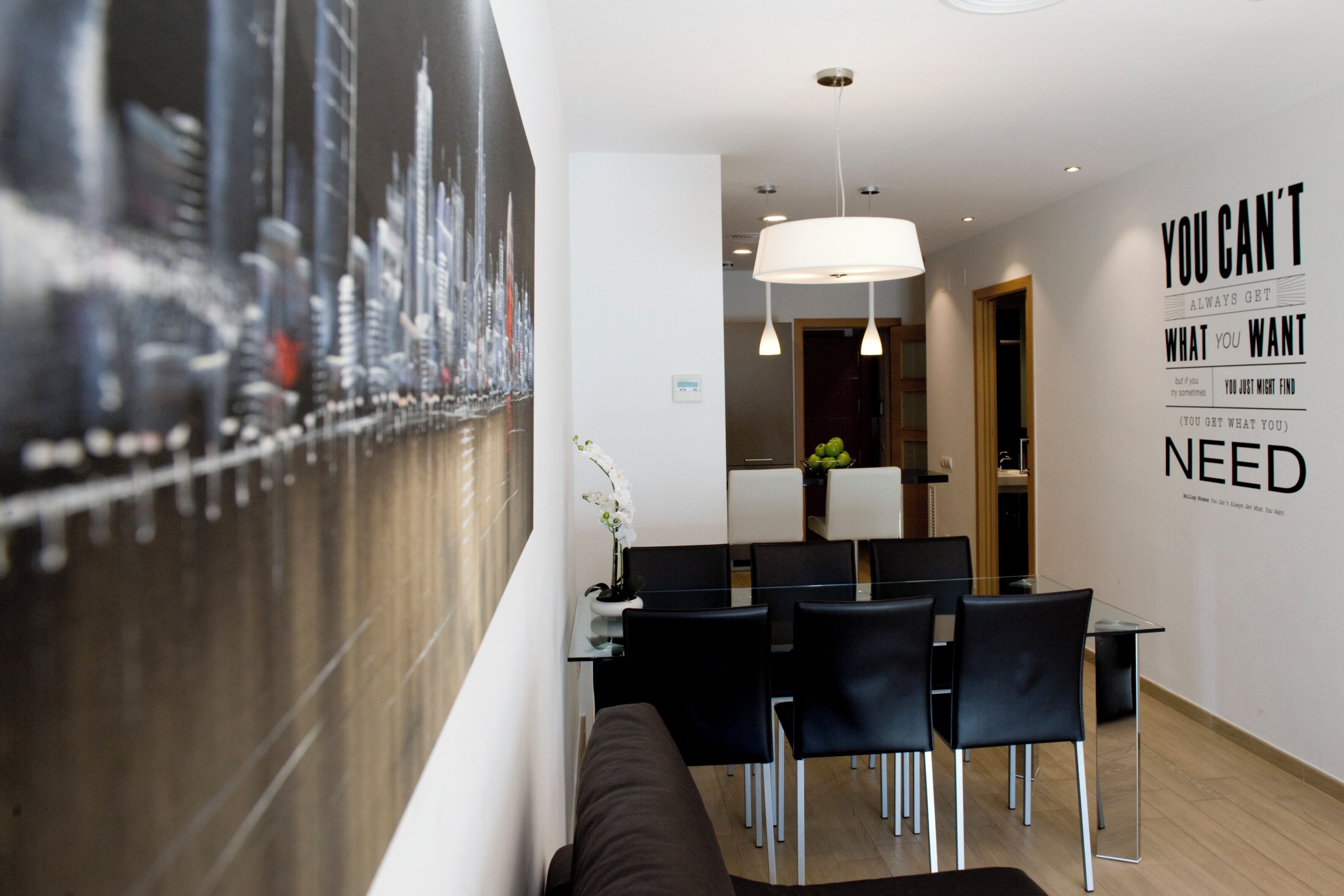 Eine moderne Hotellobby mit Stadtteil-Mural, einem Essbereich mit schwarzen Stühlen und einem Glastisch, sowie motivierenden Wandbildern.