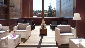 A covered outdoor seating area with wicker furniture and a central wooden table, overlooking a cityscape. - Home To Home Barcelona (Barcelona)