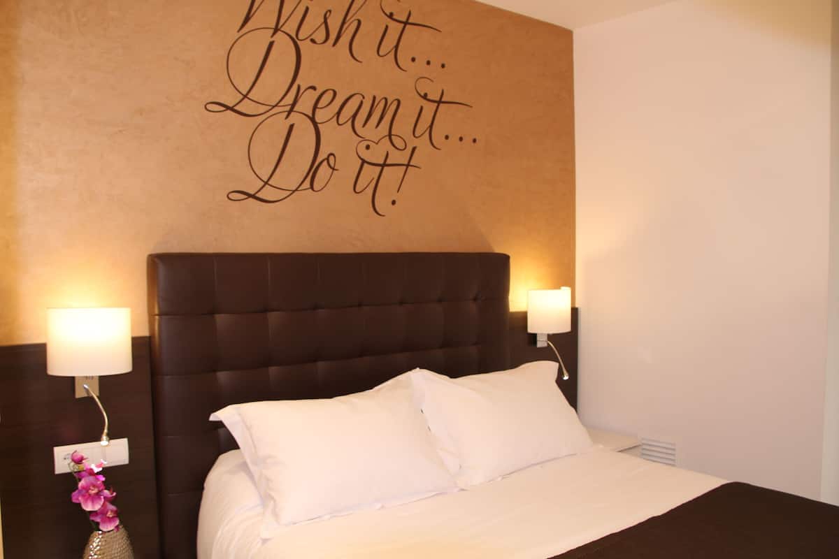 A hotel room with a large bed, two bedside lamps, and a motivational quote on the wall.