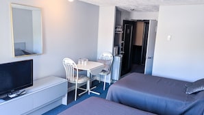 Una habitación de hotel con cama, televisión, escritorio con silla y armario.
