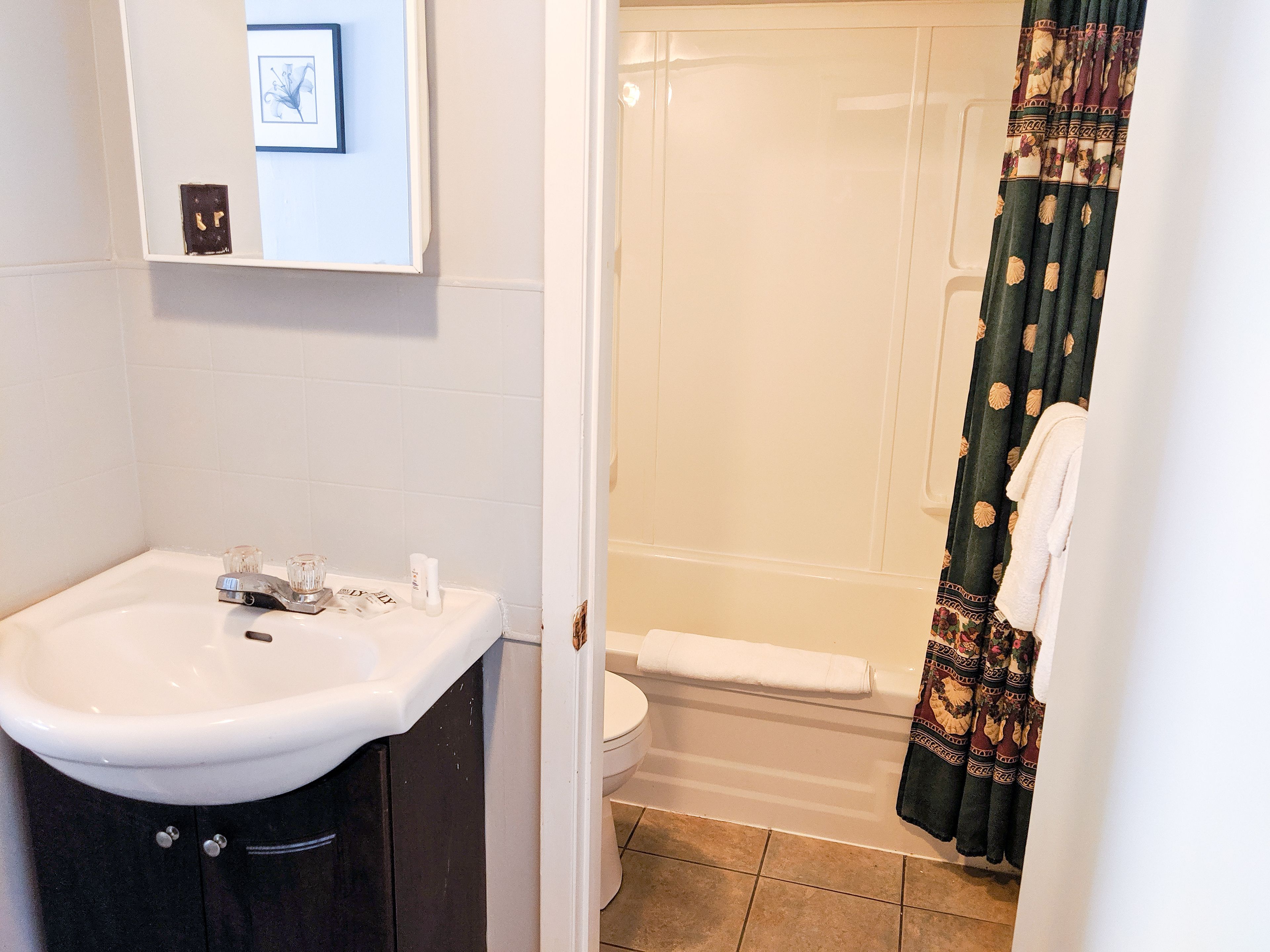 A bathroom with a white sink, toilet, and shower curtain.