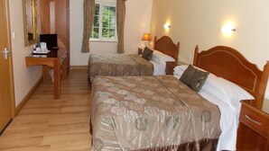 Habitación de hotel con dos camas, un escritorio con computadora, una ventana con cortinas y una lámpara.