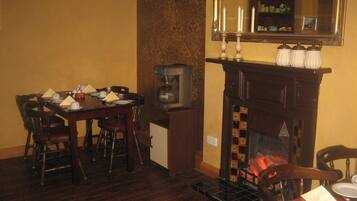 Un comedor con una mesa de madera, sillas, una máquina de café y una chimenea con repisa.