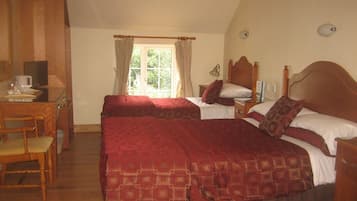 A bedroom with two beds, a wooden desk, and a window with curtains.