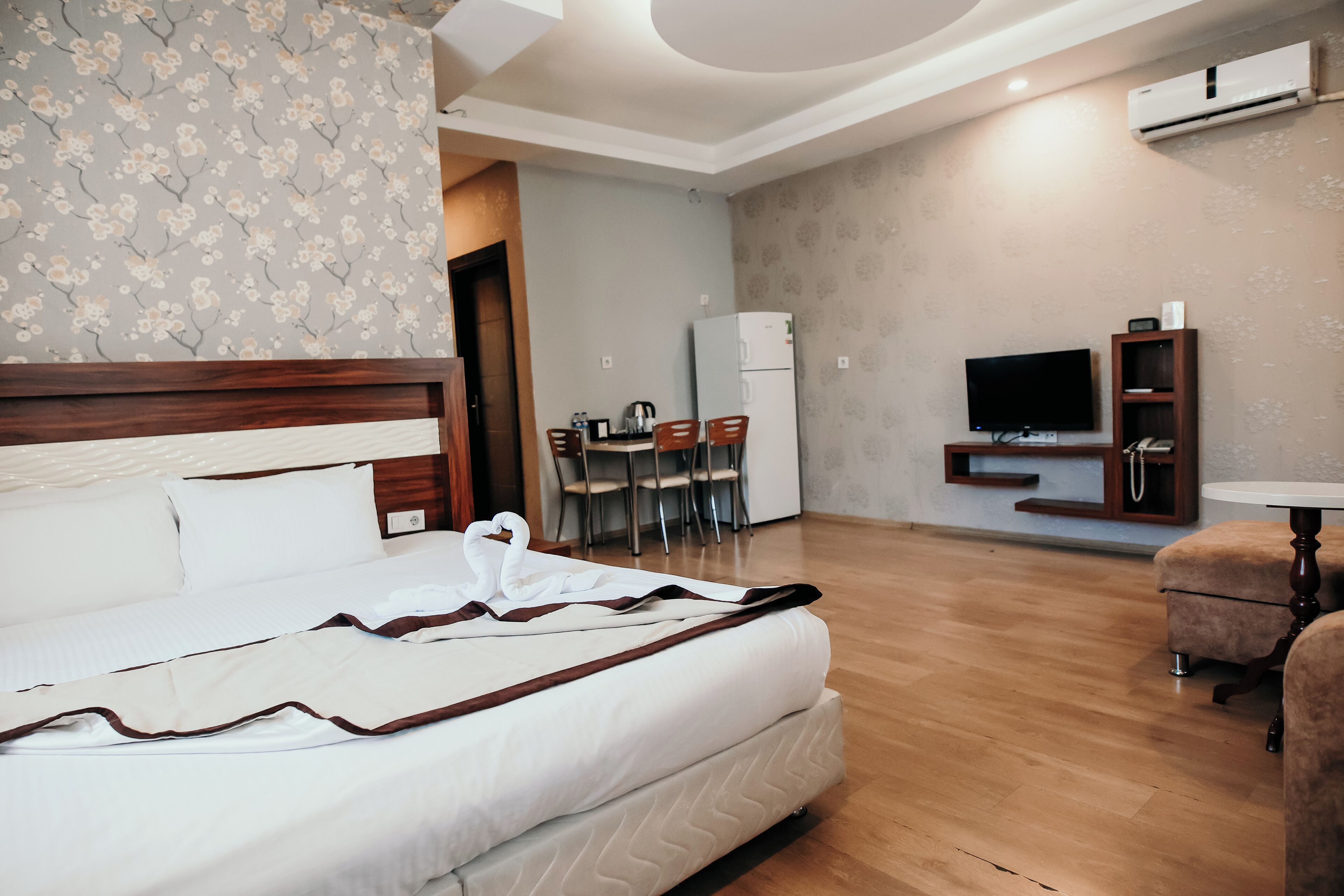 A hotel room with a bed, a dining area, a TV, and a small table.