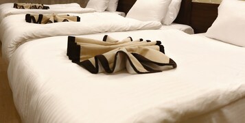 Quarto de hotel com camas bem arrumadas, cada uma com roupa de cama branca e cabeceiras pretas.