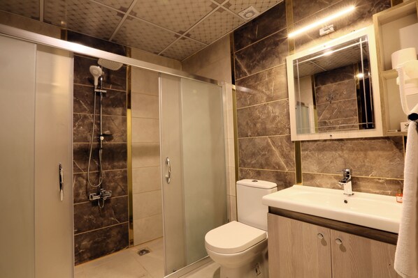A modern bathroom with a glass-enclosed shower, a toilet, a sink with a mirror, and a towel rack. - AZD House Hotel (Mardin)