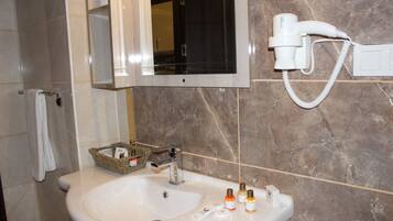 Un baño con lavabo, espejo, toallero y secador de pelo en la pared.