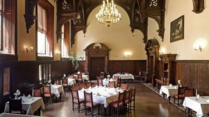Un comedor con techos altos de madera, candelabros y mesas dispuestas para comer.