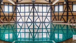 Una amplia piscina cubierta con techo alto y paredes de ladrillo visto.