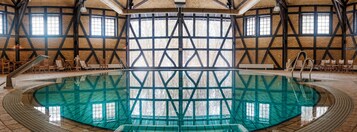 Uma grande piscina interna com teto alto e paredes de tijolo aparente.