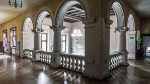 Un hallo espacioso con techos de madera altos, ventanas arqueadas y una araña.