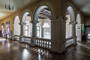 Um salão amplo com alto teto de madeira, janelas em arco e um candelabro.