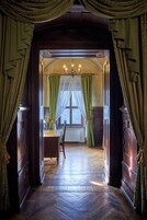 Quarto com piso em padrão herringbone, escrivaninha de madeira e janela com cortinas verdes.