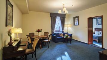 Una habitación de hotel con comedor, sofá, escritorio con lámpara y cama.