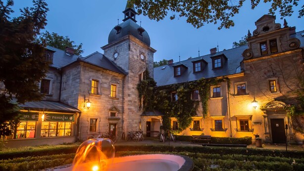 Un edificio histórico con una fuente, arquitectura de piedra y una torre del reloj.