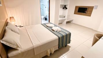 Una habitación de hotel con cama, mesita de noche, lámpara y vista al baño.