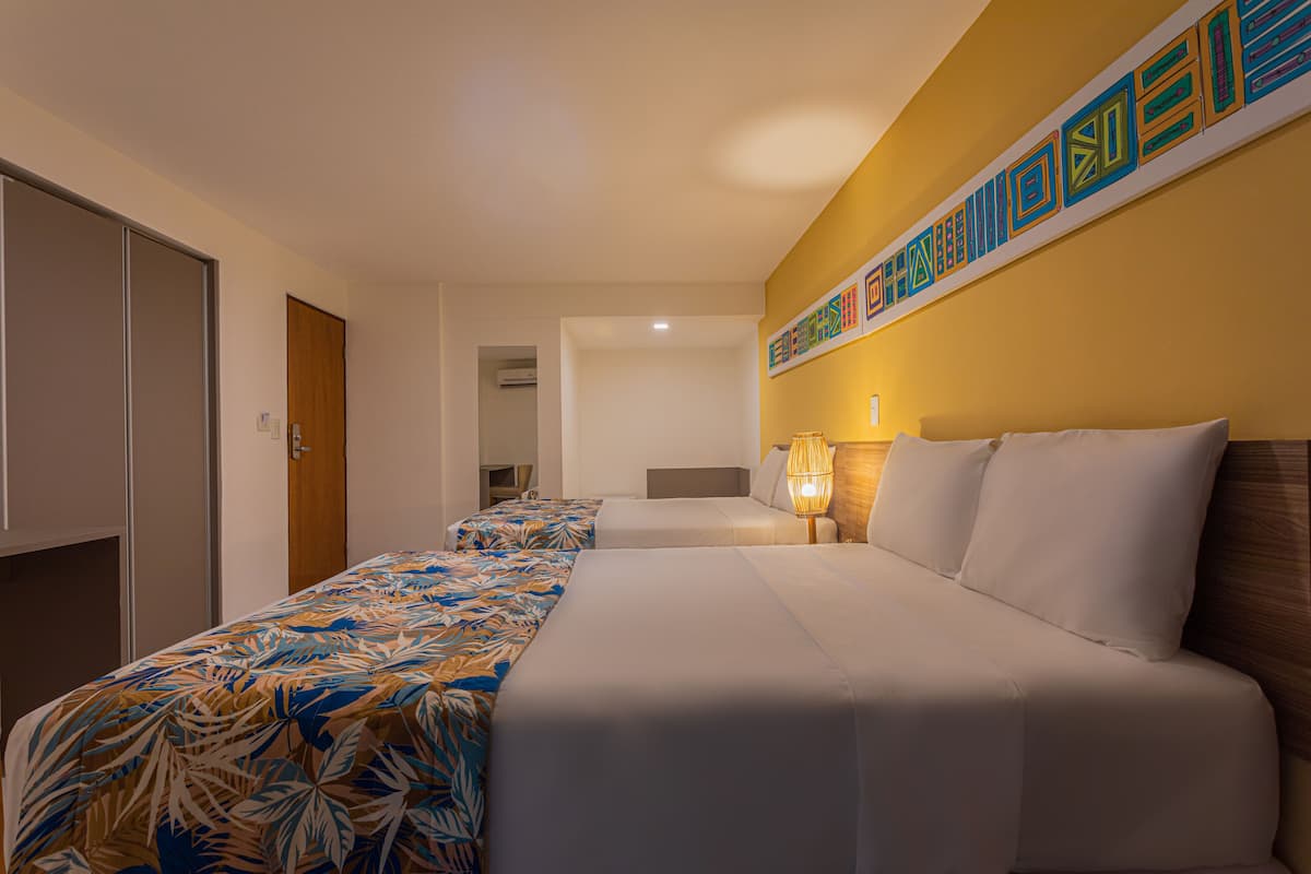 A hotel room with a bed, a nightstand, a lamp, and a wall decoration.
