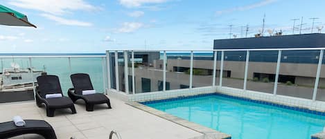 Una piscina al aire libre, sillones reclinables de piscina