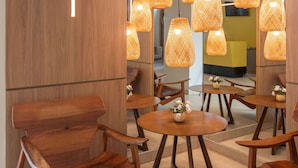 A modern interior with wooden furniture, round tables, and hanging wicker lamps. - Slim Pajuçara by Tropicalis (Maceió)
