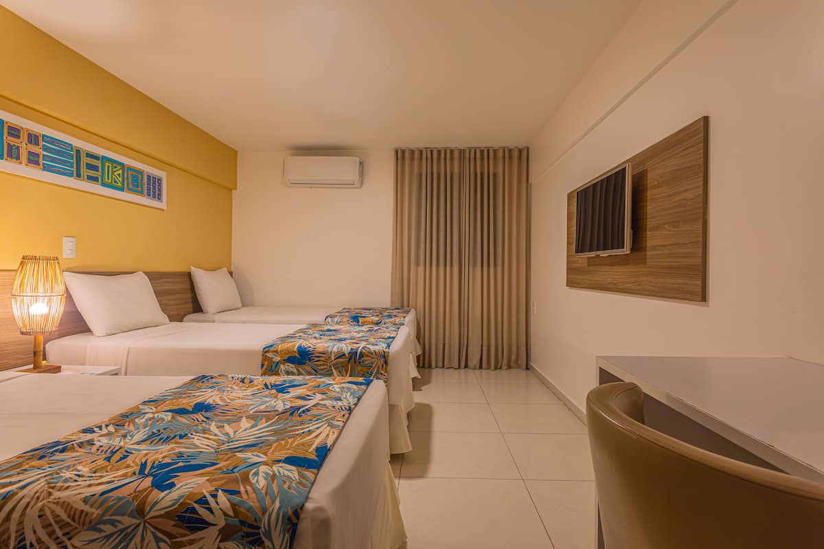 A hotel room with two beds, a desk, and a chair.